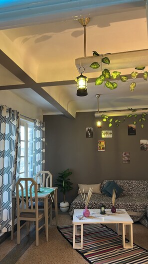 A living room with a sofa, a table, chairs, a ceiling fan, and wall decorations. - Comfortable Apartment in the Heart of Tunis – Explore the City Easily (Tunis)