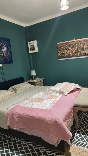 Ein Schlafzimmer mit einem Bett, einem Nachttisch, einer Lampe und zwei Wandbildern.