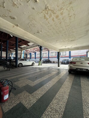 An indoor parking area with cars parked, a fire extinguisher, and a visible ceiling with some damage. - Comfortable Apartment in the Heart of Tunis – Explore the City Easily (Tunis)