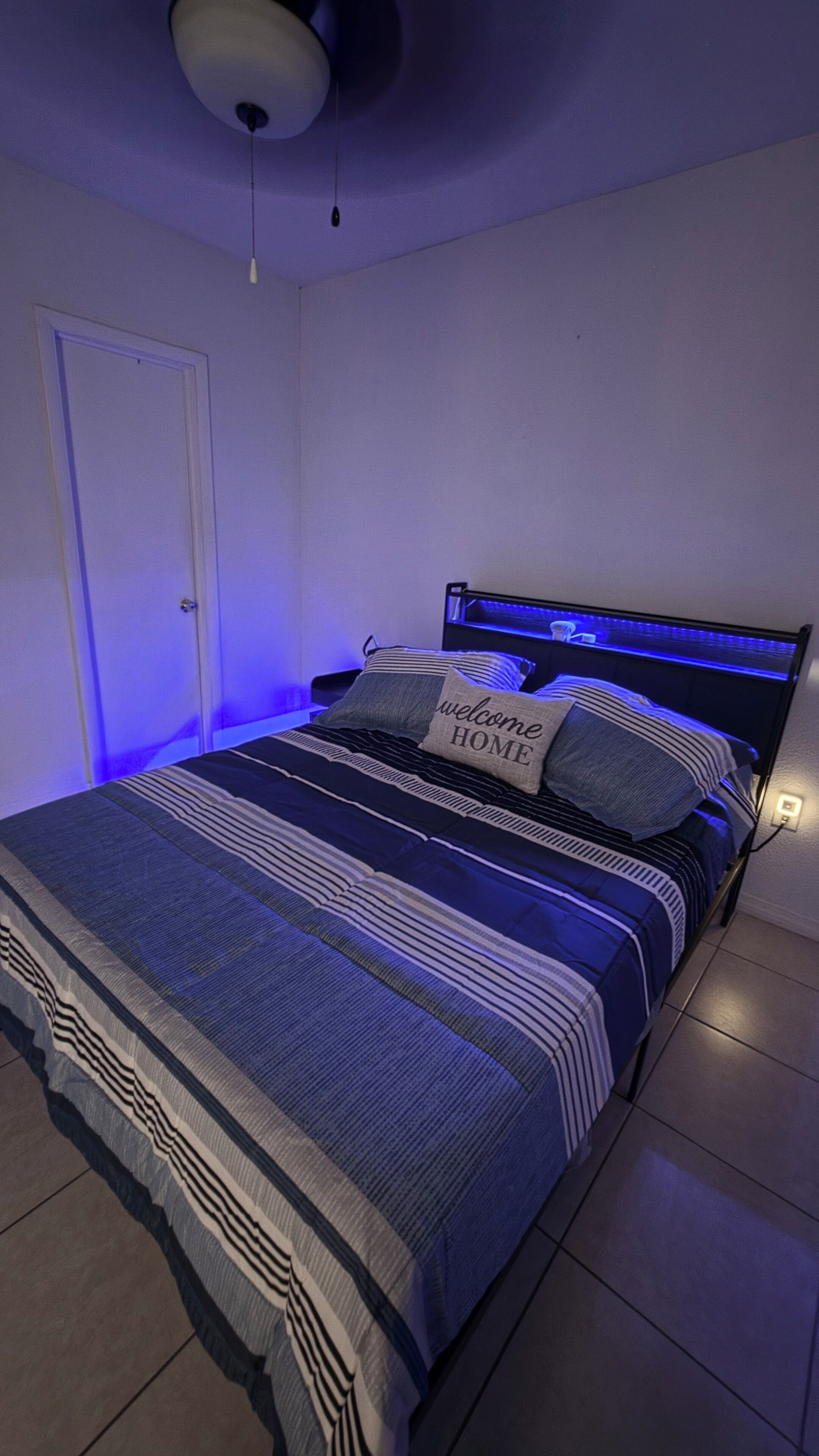 Une chambre à coucher avec un lit, une table de chevet et une commode, ainsi qu’une porte.