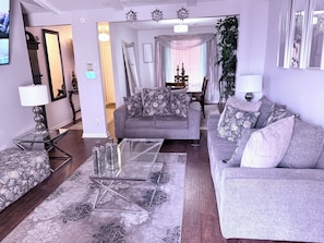 A living room with a grey sofa, patterned cushions, a glass coffee table, and a decorative rug. - Spacious 3BR Retreat • Quiet Neighborhood • Minutes to Downtown (Little Rock)