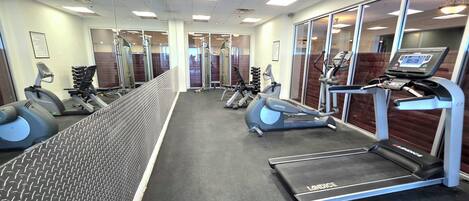 A gym with treadmills, elliptical machines, and weight equipment.