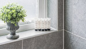 Ein Ablagefach im Badezimmer mit Pflegeprodukten und einer Topfpflanze.