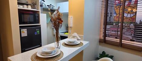 A modern kitchen with a central island, two bar stools, a refrigerator, and a microwave.