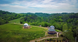 Un bâtiment en forme de dôme, entouré d’une végétation luxuriante et situé dans un paysage vallonné.