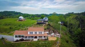 Ein großes Haus mit breiter Veranda, Garten und zwei kuppelartigen Bauten.