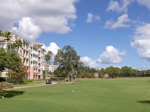 A golf course with a clubhouse, palm trees, and a building with balconies. - King Villa Resort with Balcony near Orlando’s I-Drive (Orlando)
