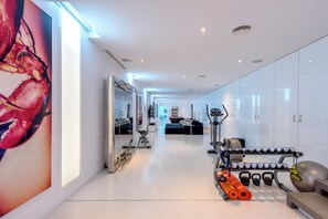 A modern, well-lit hallway with a large mirror, exercise equipment, and a gym area. - Villa Jondal (Jesús)