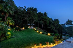 A well-maintained garden with a lawn, trees, and a seating area with tables and chairs. - Villa Jondal (Jesús)