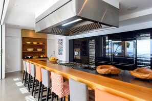 A modern kitchen with a central island, stainless steel appliances, and a large window. - Villa Jondal (Jesús)