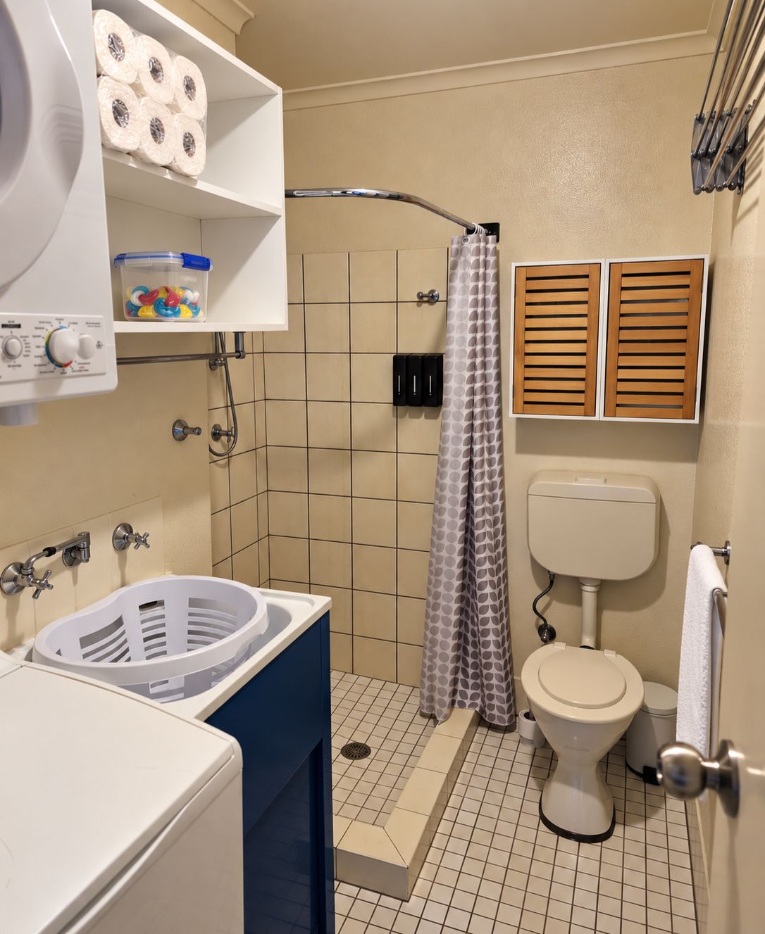 A bathroom with a shower, toilet, and a washing machine.