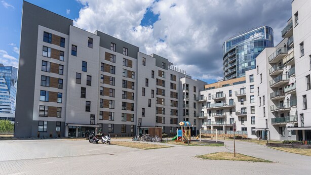 Um edifício residencial moderno, de vários andares, com telhado plano, grandes janelas e uma área de recreação.