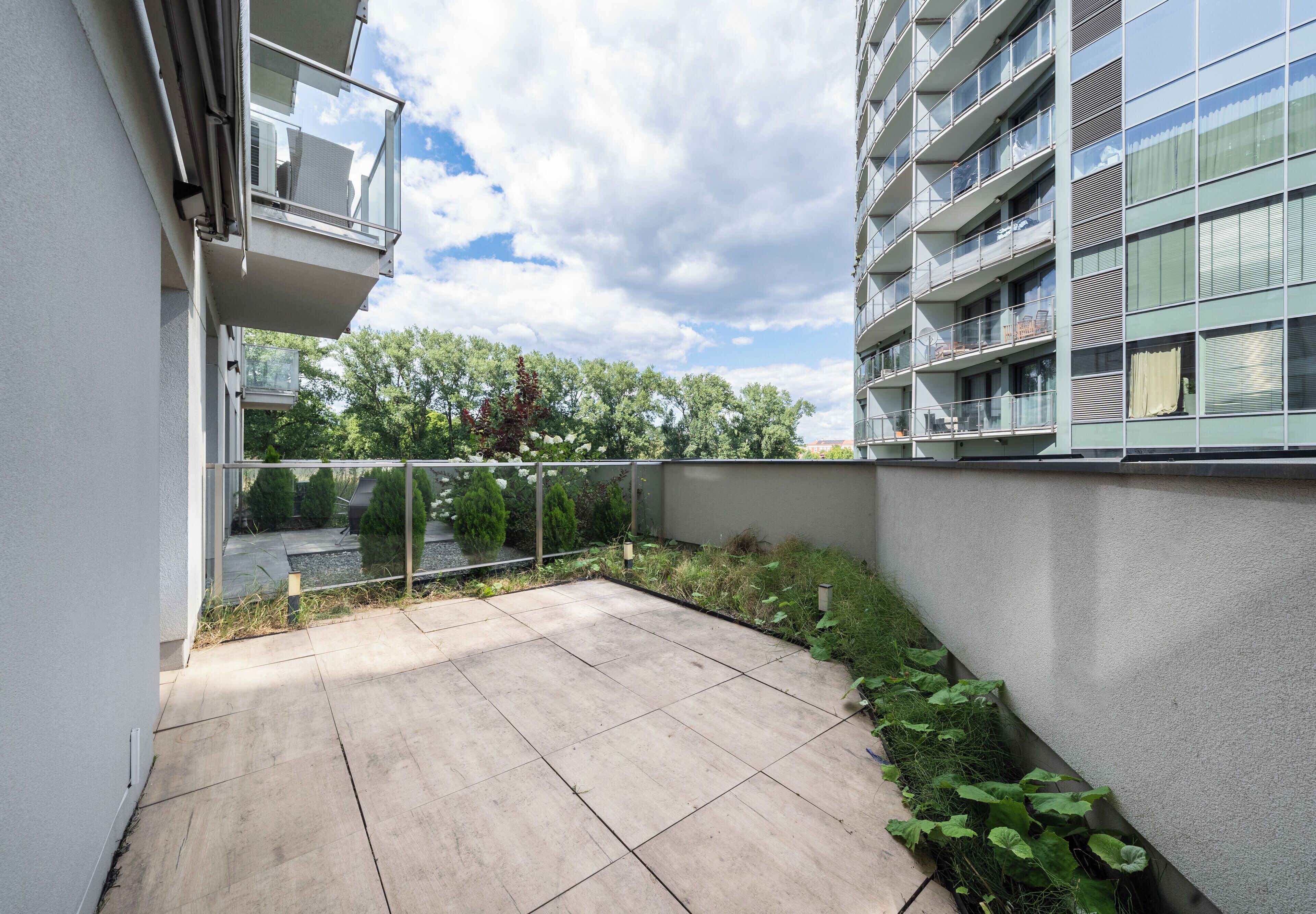 Un moderno complejo de apartamentos con patio, balcones y vista a árboles.