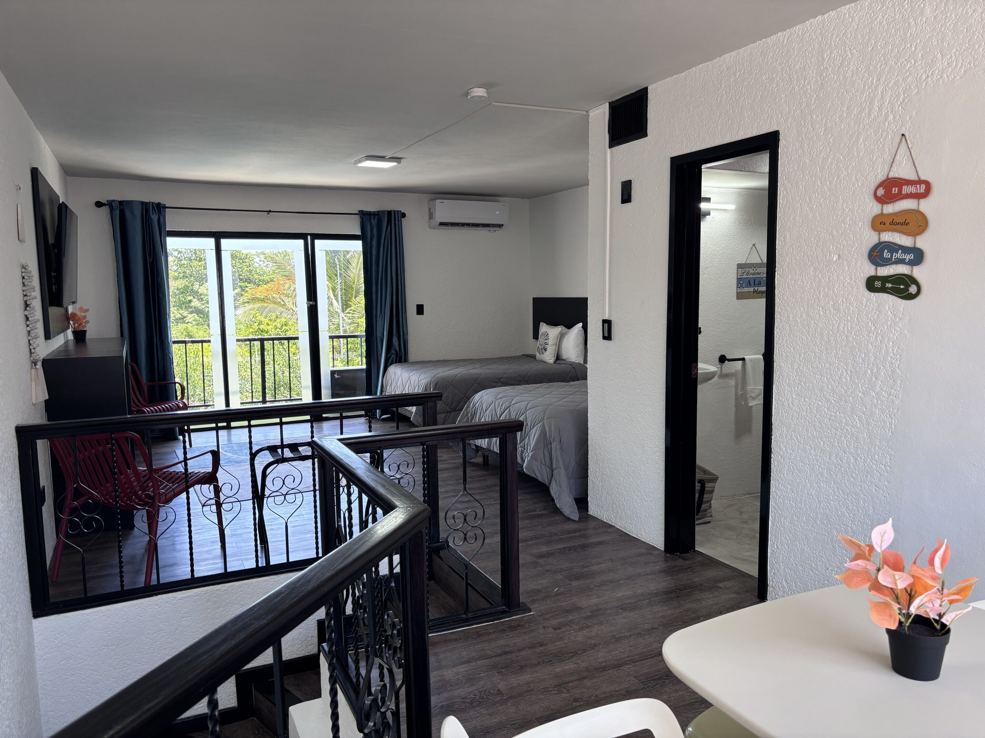 A hotel room with a balcony, a bed, a desk, and a dining area.