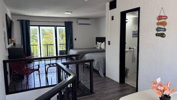 A hotel room with a balcony, a bed, a desk, and a dining area.