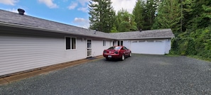 Une maison de plain-pied avec une voiture rouge garée dans l’allée.