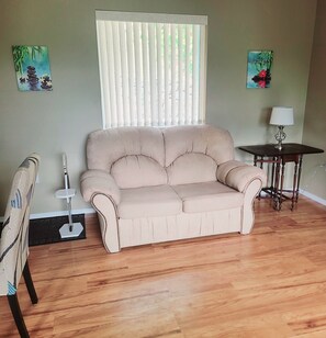 A beige sofa, a small table with a lamp, and two paintings on the wall.