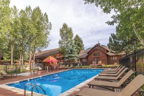 A swimming pool with lounge chairs and a wooden building in the background. - Private 2-bedroom luxury cabin in Estes Park with cozy charm (Estes Park)