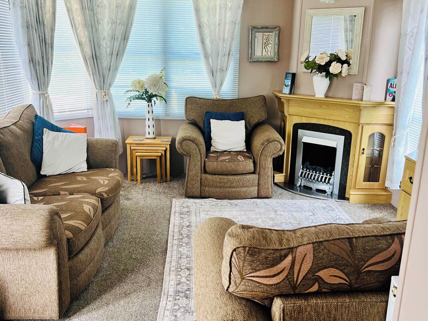 A living room with a sofa set, a fireplace, and a small table with a vase of flowers.