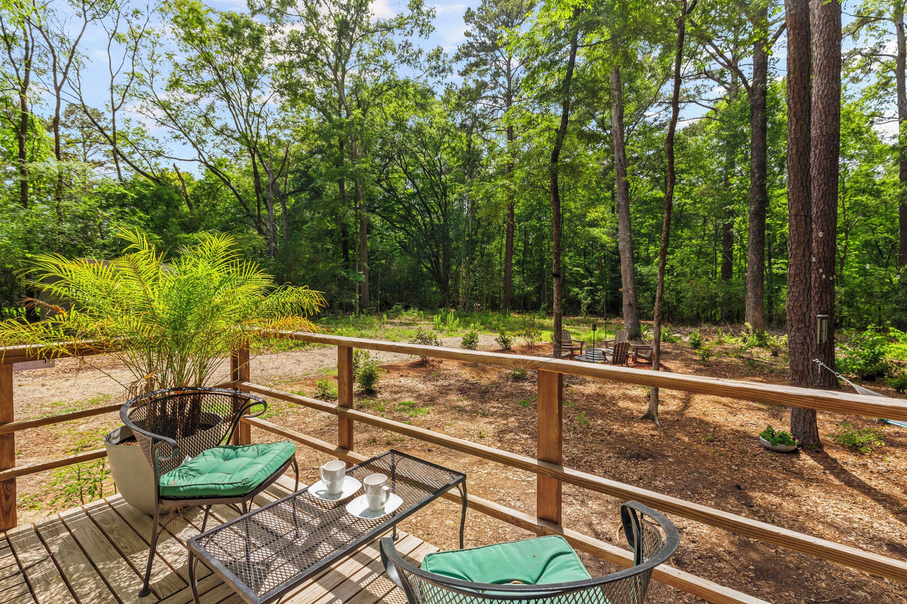 Un patio in legno con tavolo e sedie, immerso in una foresta.