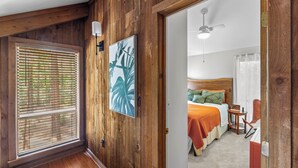 Ein Zimmer mit Holzeinrichtung, einem Bett, einem Nachttisch und einem Deckenventilator.