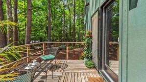Eine Holzterrasse mit Gartenmöbeln, umgeben von Bäumen.