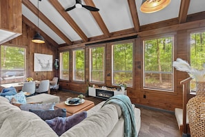A cozy interior with wooden beams, large windows, a fireplace, and comfortable seating.