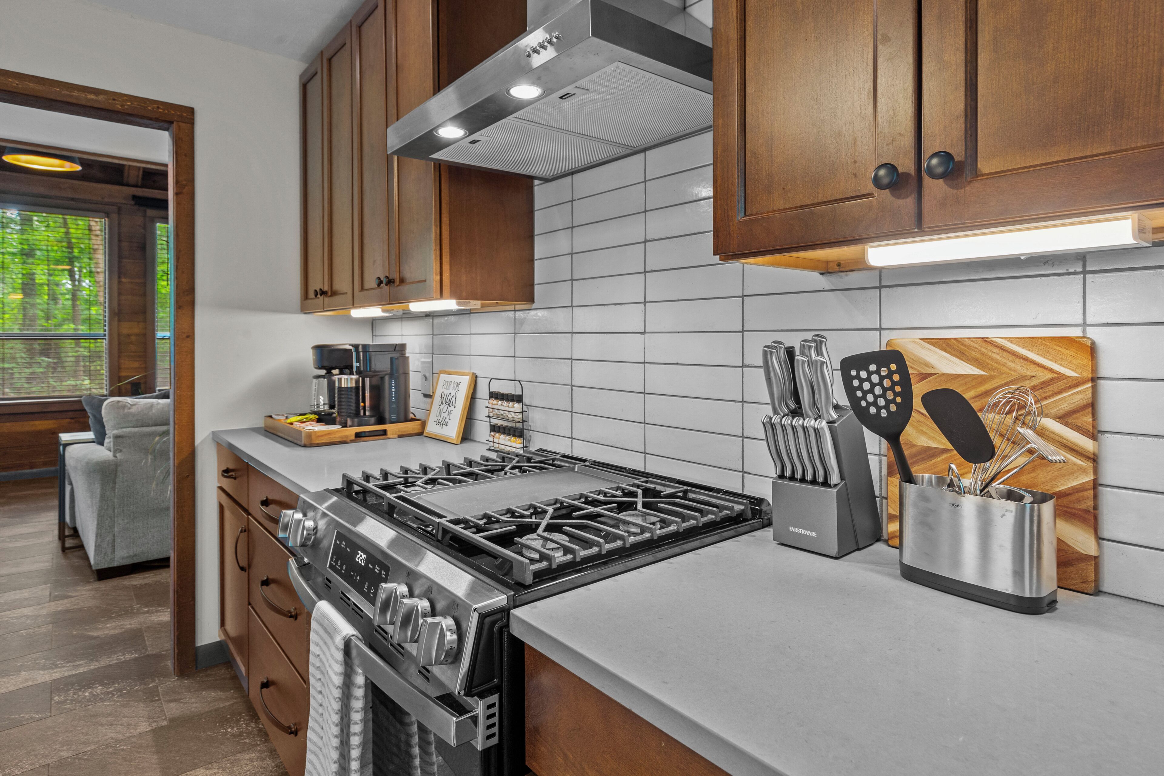 A modern kitchen with stainless steel appliances, wooden cabinets, and a tiled backsplash.