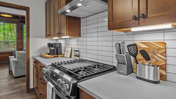 A modern kitchen with stainless steel appliances, wooden cabinets, and a tiled backsplash.