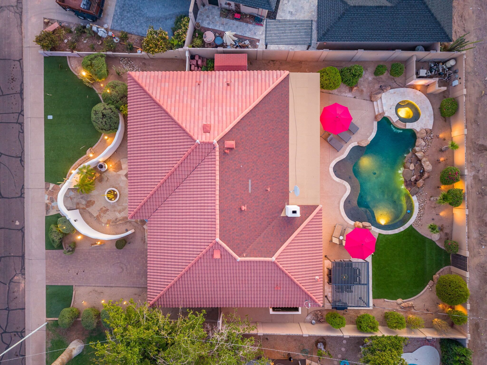 An aerial view of a property with a red-roofed building, a swimming pool, and landscaped areas.