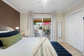 A hotel room with a bed, a seating area with chairs, a large window, and a door. - NEW|Iconic Granada Grotto|Pool & Hottub| Sleeps 12 (Scottsdale)