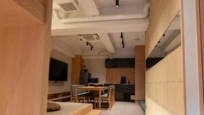 A modern interior with a long corridor leading to a dining area, wooden furniture, and a kitchen in the background. - Villa Customa (Taito City)