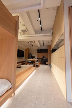 Ein modernes Interieur mit einem langen Korridor, der zu einem Essbereich führt, Holzmöbeln und einer Küche im Hintergrund.