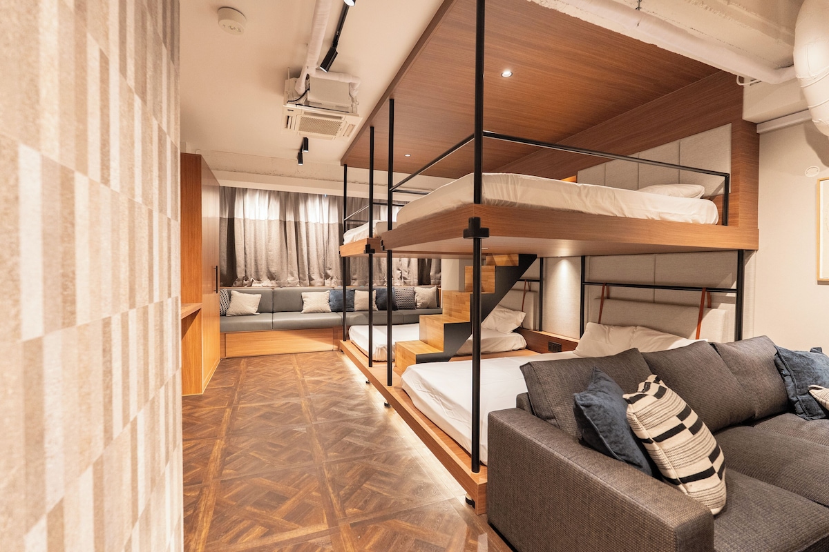 Ein modernes Hotelzimmer mit Etagenbett, Sofa und Holzboden.