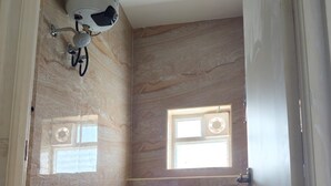 Een badkamer met toilet, douche en emmer.