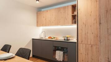 Une cuisine moderne avec des meubles en bois, un four encastré et un coin repas comprenant une table et des chaises.