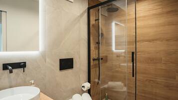 Ein modernes Badezimmer mit einer gläsernen Dusche, einem weißen Waschbecken und einer Holzkommode.