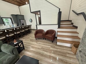 A modern interior with a staircase, wooden flooring, a dining area, and a kitchen.
