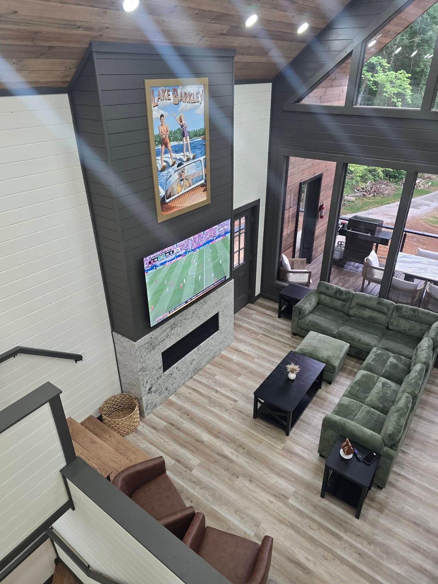 Uma sala de estar moderna com televisão de tela plana, lareira e uma grande janela com vista para um jardim.