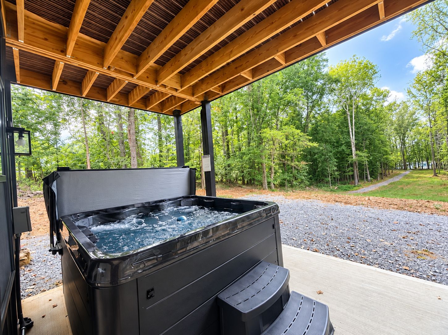 An outdoor hot tub with a wooden deck and a view of a forested area.