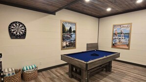 A room with a pool table, two dartboards, and two posters of Lake Barkley.