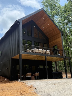 A modern two-story building with a balcony, large windows, and a wooden ceiling.