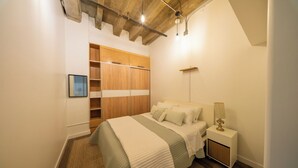Un dormitorio con cama, mesita de noche, lámpara y armario.