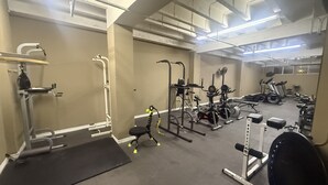 Un gimnasio con diversos equipos de ejercicio, incluyendo una cinta de correr, banco de pesas y pesas sueltas.