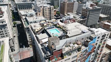 Ein Hochhaus mit mehreren Stockwerken, einem Dachpool und der umliegenden Stadtlandschaft.
