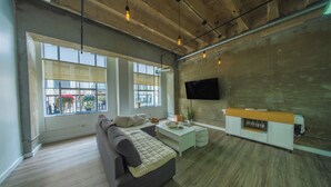 Una sala de estar moderna con un sofá, una mesa de centro y un televisor montado en una pared de concreto.