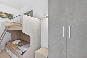 Ein Etagenbett mit einer Leiter, ein Nachttisch und ein Kleiderschrank mit zwei Türen.