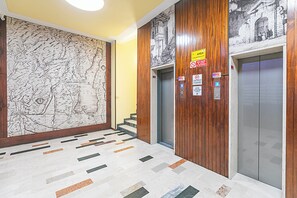 Eine Lobby mit einer großen Karten-Wandmalerei, einem Aufzug und einer Treppe.