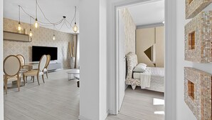 Ein modernes Interieur mit Essbereich, Flachbildfernseher und einem Bett mit gemustertem Kopfteil.