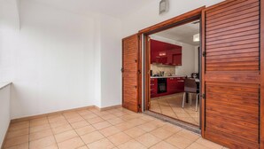 A room with a wooden door leading to a kitchen with red cabinets and a tiled floor. - Budoni Beach Homes, Budoni, Italy (Budoni)